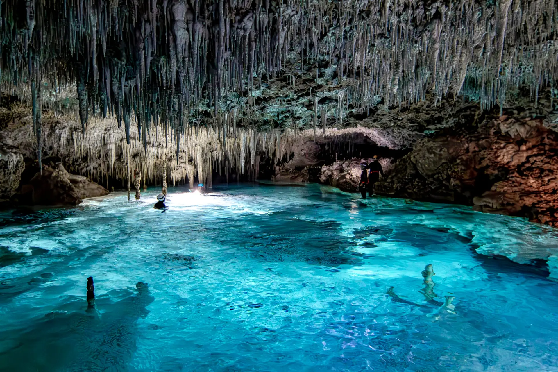 Clear blue cenote surrounded by limestone formations